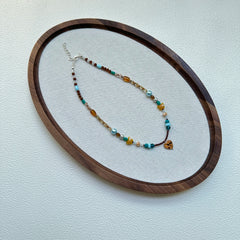 Close-up of amber heart glass pendant with ocean-turquoise bead