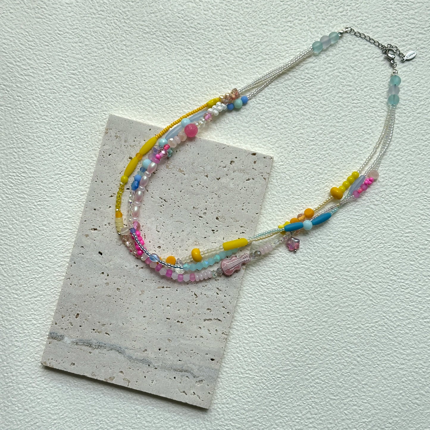 Sunshine Confetti Necklace styled in a loop on a textured card – cheerful pastel beads with subtle crystal shine