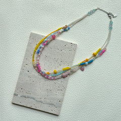 Sunshine Confetti Necklace styled in a loop on a textured card – cheerful pastel beads with subtle crystal shine