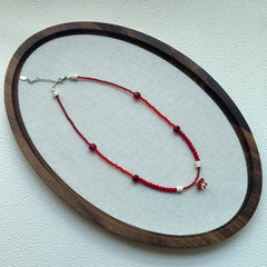 Crimson Toadstool Necklace displayed on oval tray, handmade red bead necklace with ivory details and mushroom charm