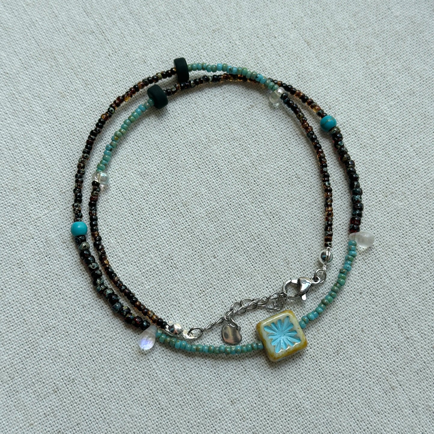 Azure Blossom Necklace displayed flat with turquoise accents and unique ceramic flower pendant