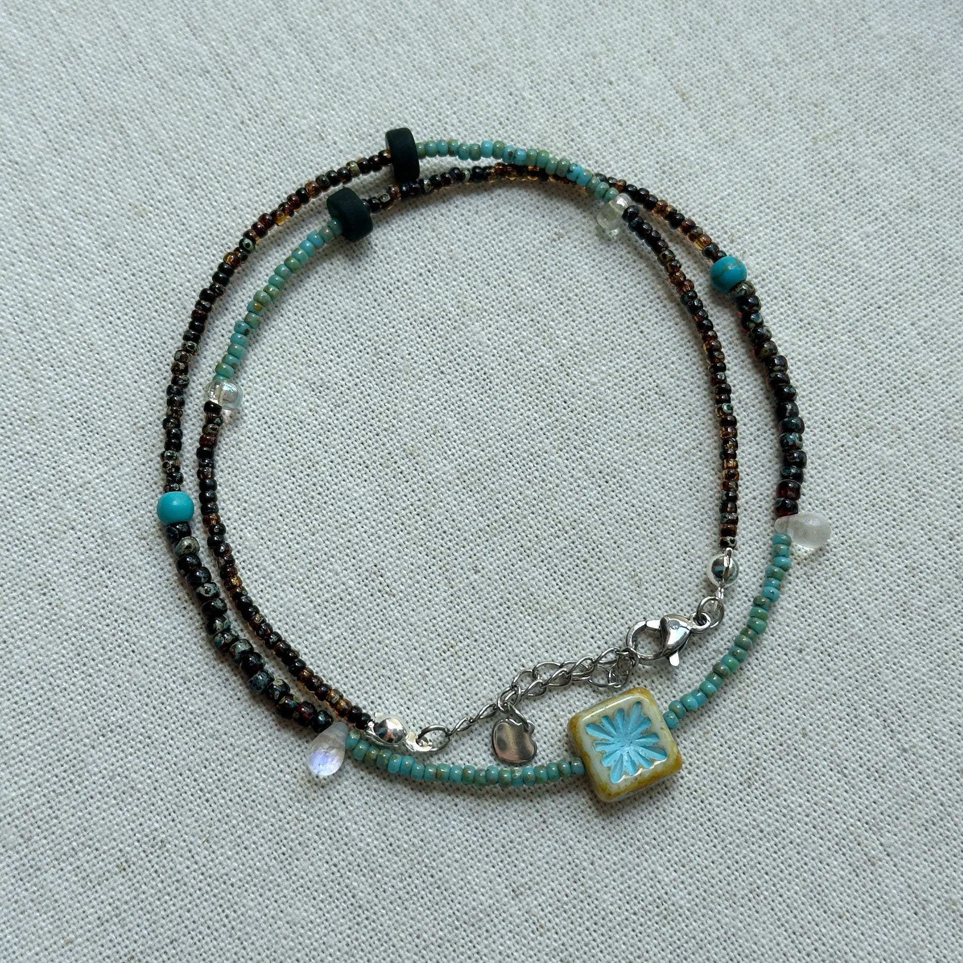 Azure Blossom Necklace displayed flat with turquoise accents and unique ceramic flower pendant
