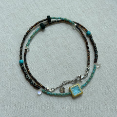 Azure Blossom Necklace displayed flat with turquoise accents and unique ceramic flower pendant