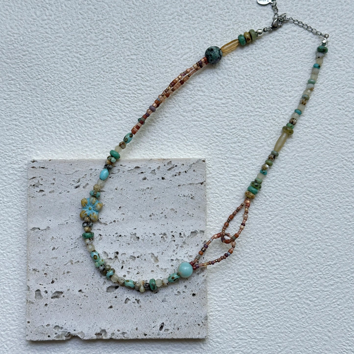 Close-up of Sage Loop Blossom Necklace showing the double-loop links, mint beads, and the soft floral focal with sandy accents
