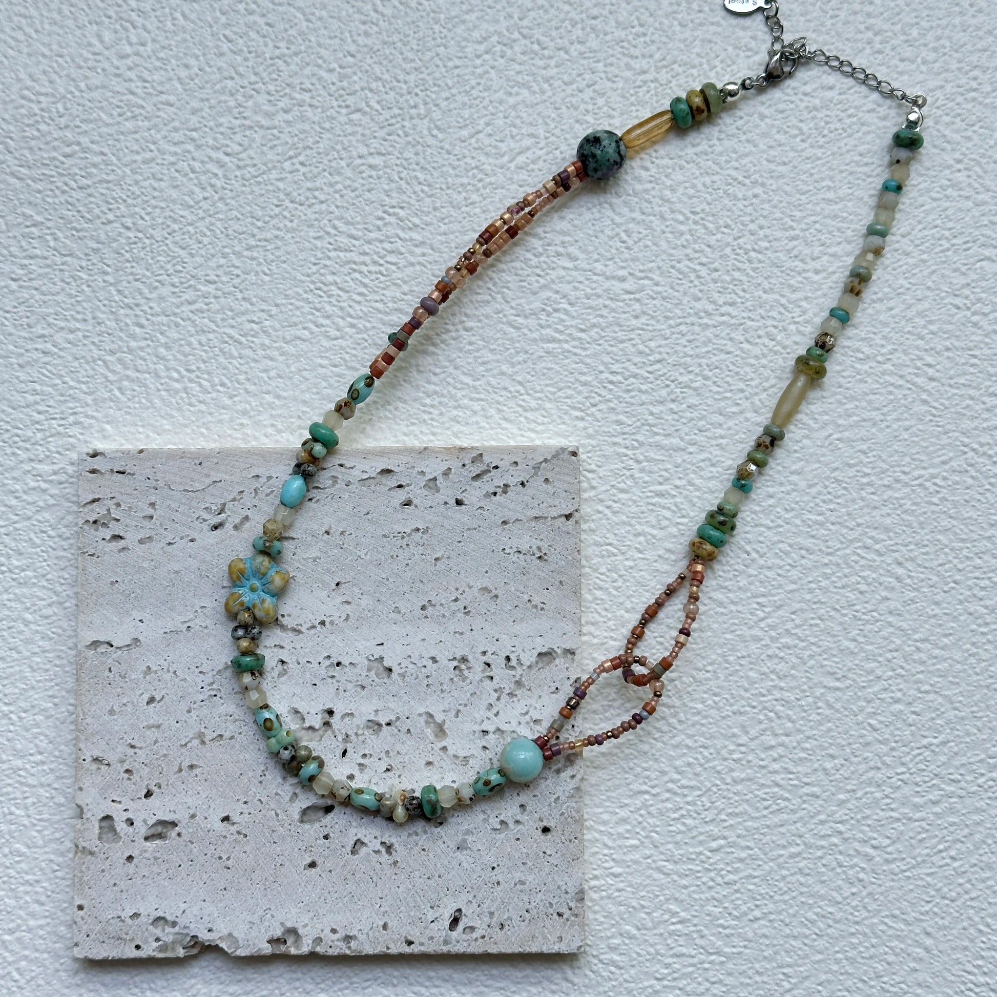 Close-up of Sage Loop Blossom Necklace showing the double-loop links, mint beads, and the soft floral focal with sandy accents