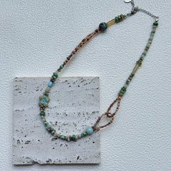 Close-up of Sage Loop Blossom Necklace showing the double-loop links, mint beads, and the soft floral focal with sandy accents