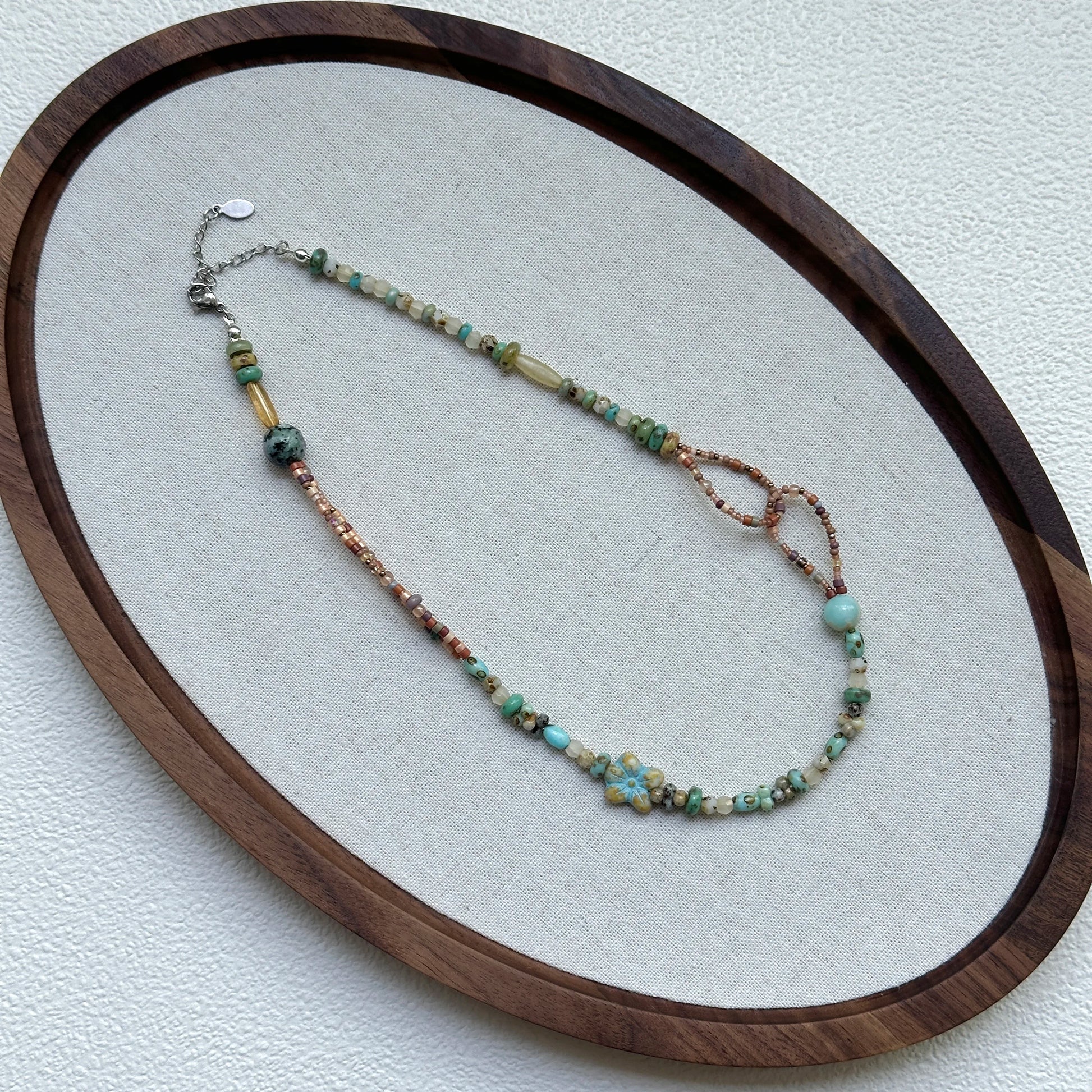 Full view of Sage Loop Blossom Necklace hanging – handcrafted dune palette with modern asymmetrical loop detail