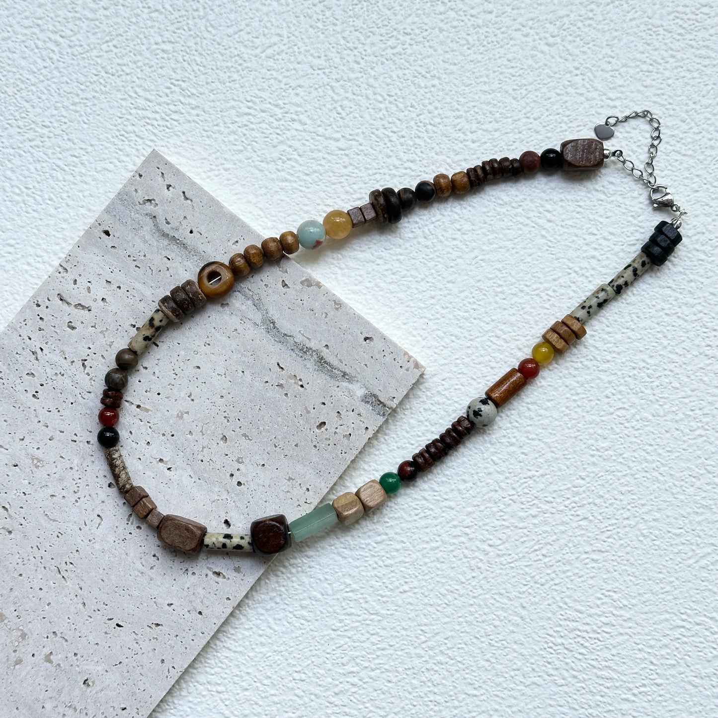 Flat lay of Desert Caravan Necklace on textured card – earthy sand and terracotta tones with olive and teal pops