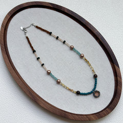 Full view of Lagoon Sunburst Necklace hanging – handcrafted coastal palette of lagoon blue and gold with sunburst focal