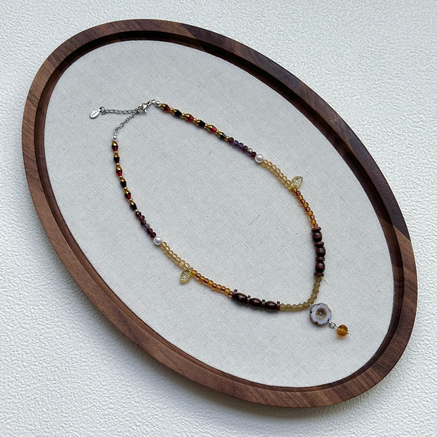 Amber Daisy Necklace displayed on an oval tray – delicate amber–gold palette with daisy pendant and petite amber drop