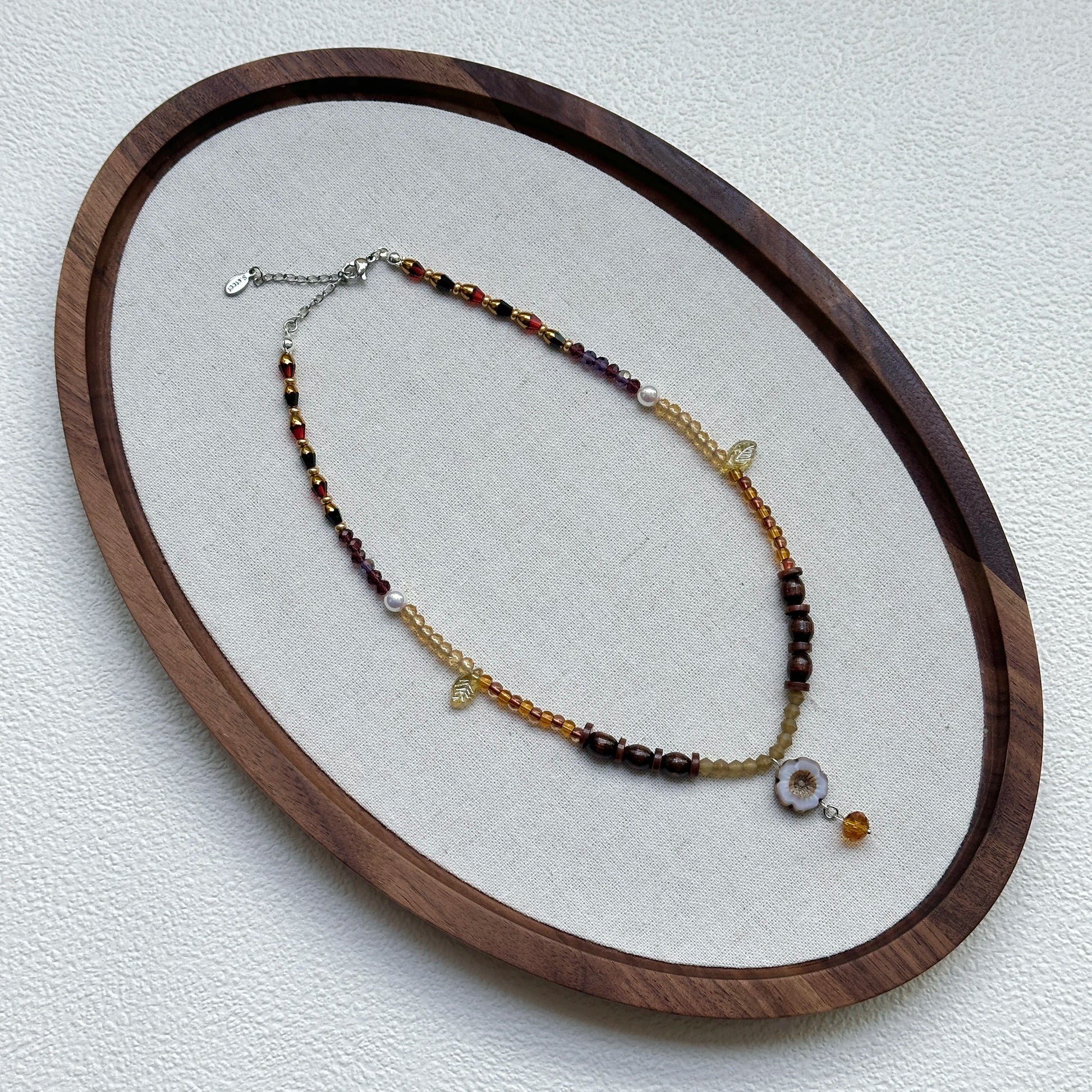 Amber Daisy Necklace displayed on an oval tray – delicate amber–gold palette with daisy pendant and petite amber drop