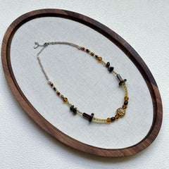 Marigold Ember Necklace displayed on an oval tray – warm amber, brown, and green beads with sunburst centerpiece