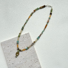 Verdant Amulet Necklace styled on white background – handmade necklace with earthy glass beads and amulet-inspired charm pendant by Glazenya