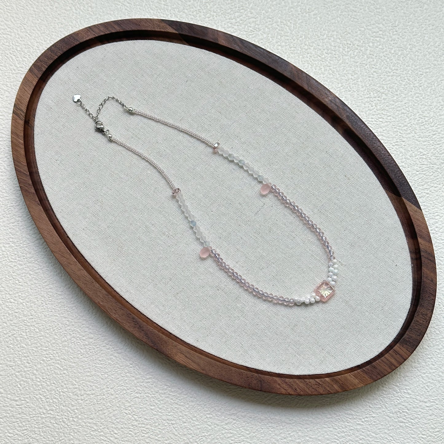 Blush Crystal Necklace oval flat lay – handmade blush and clear glass beaded necklace with minimalist crystal focal design by Glazenya