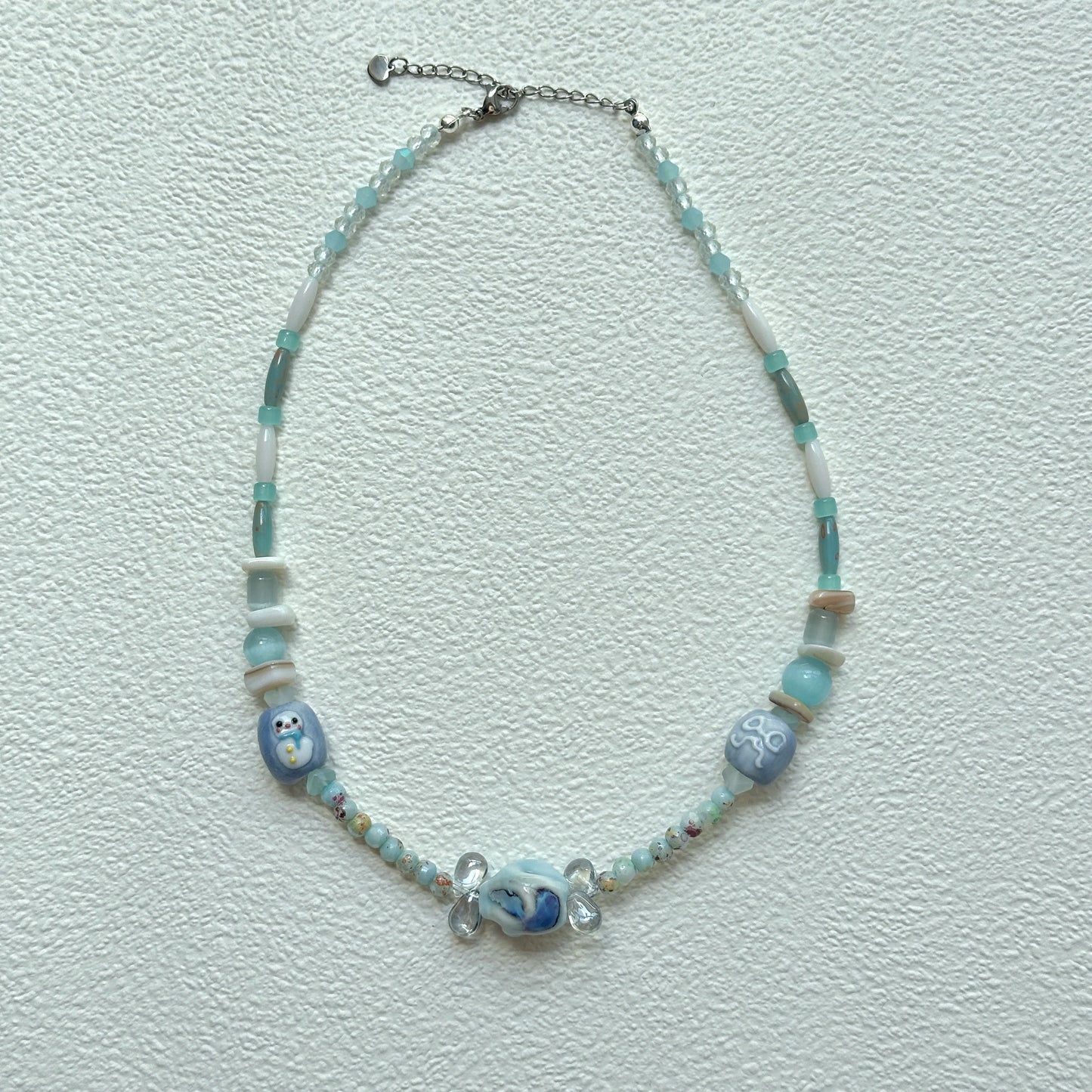 Close-up of Ocean Whisper Necklace with marbled centerpiece bead and sea-inspired charms.