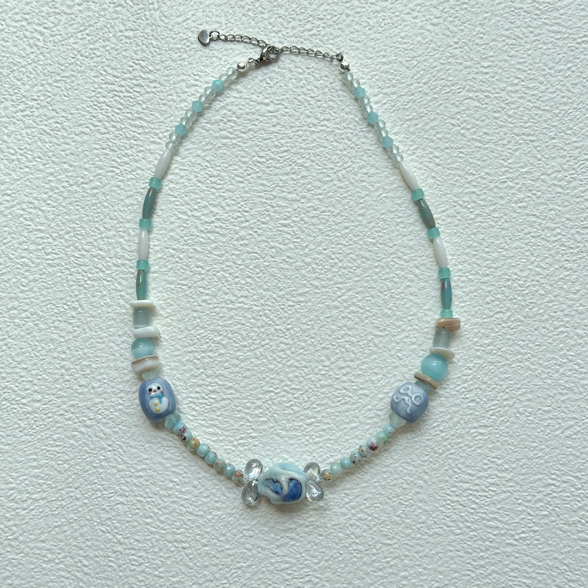 Close-up of Ocean Whisper Necklace with marbled centerpiece bead and sea-inspired charms.