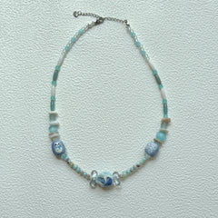 Close-up of Ocean Whisper Necklace with marbled centerpiece bead and sea-inspired charms.
