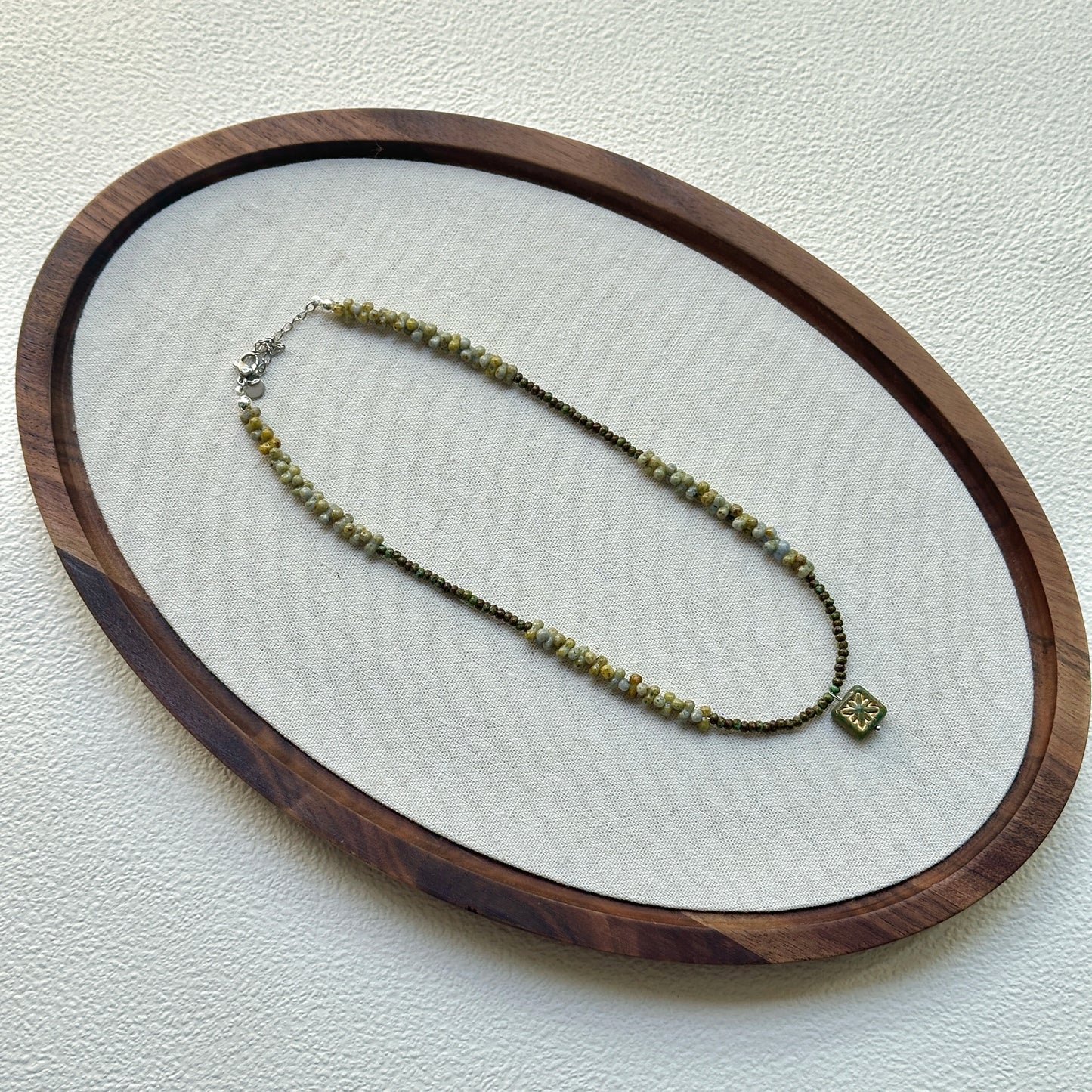 Handcrafted Gilded Bloom Necklace laid flat showing gold-accented beads and floral charm