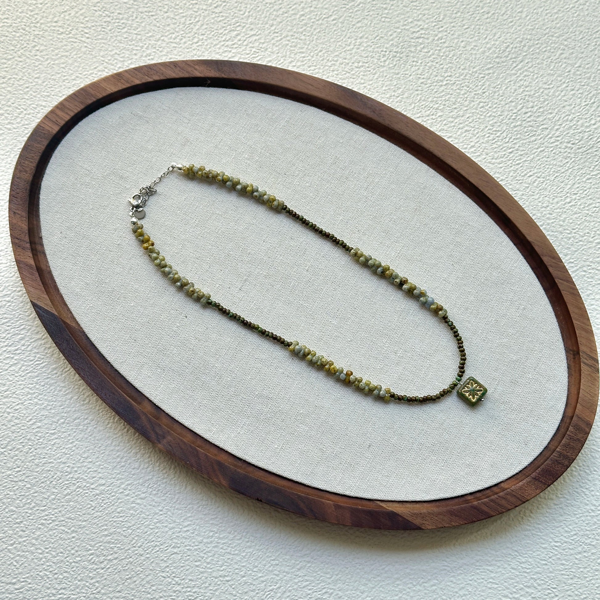 Handcrafted Gilded Bloom Necklace laid flat showing gold-accented beads and floral charm