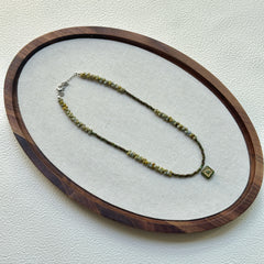 Handcrafted Gilded Bloom Necklace laid flat showing gold-accented beads and floral charm
