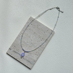 Handmade Aurora Dew Necklace laid flat, showing iridescent beads and delicate pendant details