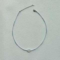Minimalist Dawn Halo Necklace laid flat with delicate seed beads and circular engraved charm
