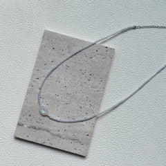 Minimalist Dawn Halo Necklace laid flat with delicate seed beads and circular engraved charm2