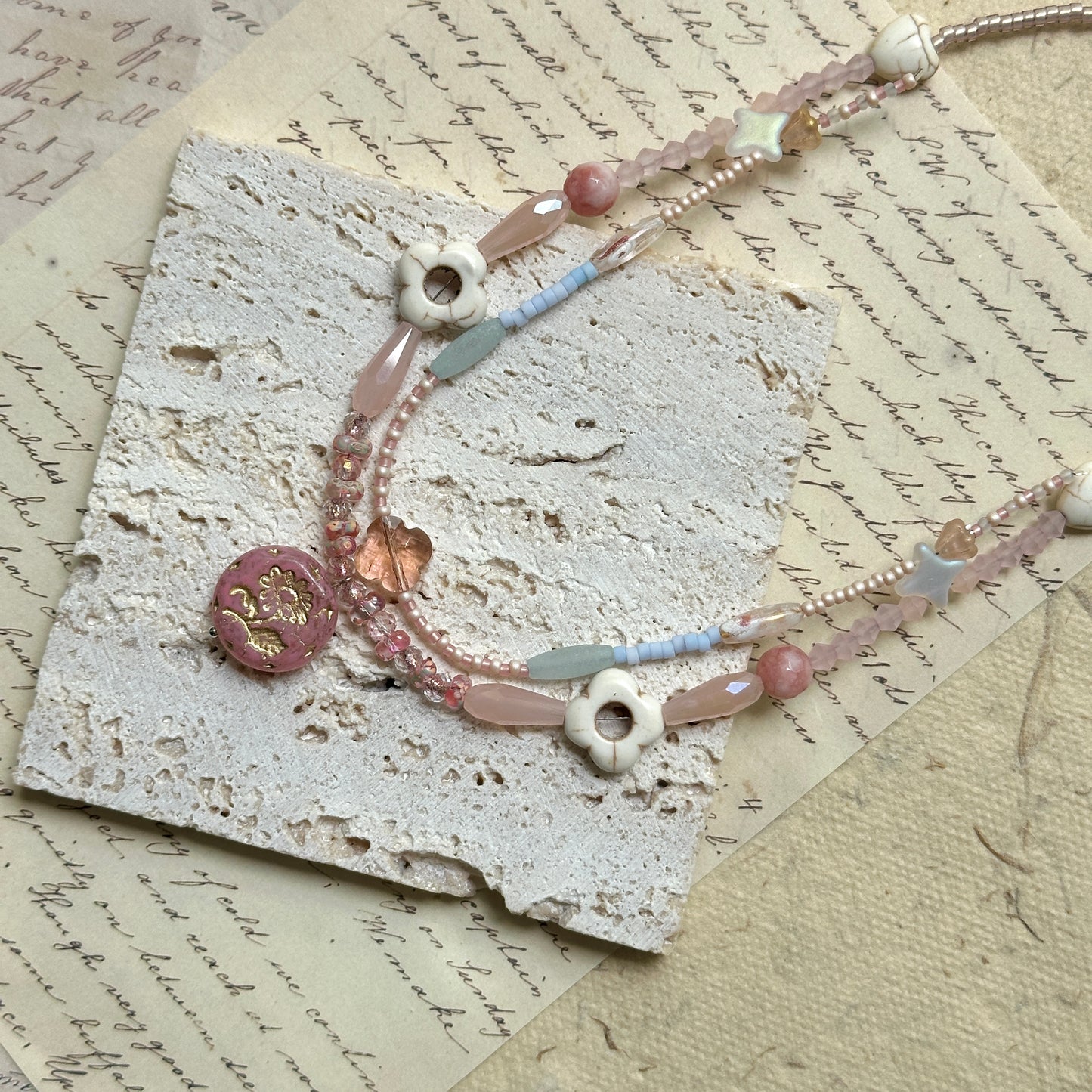 Sakura Medallion Necklace — circle layout on textured paper showing pastel bead palette and sakura medallion detail
