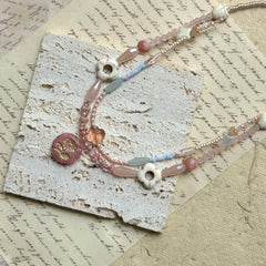 Sakura Medallion Necklace — circle layout on textured paper showing pastel bead palette and sakura medallion detail