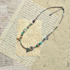 Seafoam Petal Necklace — angled view on textured paper highlighting the bead mix and petal-shaped accent detail