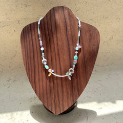 Seafoam Petal Necklace on wood display bust — pastel beads in seafoam, lilac and pearl-white with floral and petal-shaped accents