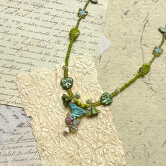 Limeleaf Bouquet Necklace — top-down view on textured paper; full necklace in lime and soft-green tones with leaf/butterfly details