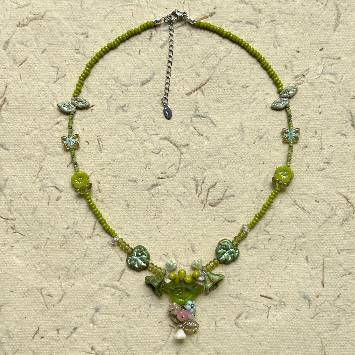 Limeleaf Bouquet Necklace — circle layout on neutral textured paper showing bead palette and bouquet-style charm