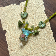 Limeleaf Bouquet Necklace — angled close-up on textured paper highlighting the bouquet-style focal, lime beads, and leaf accents