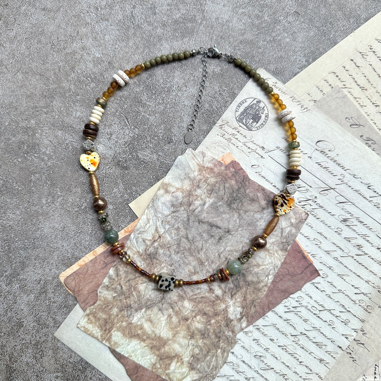 Sage & Saffron Necklace — circle layout on vintage papers; sage-green and saffron-amber palette with speckled hearts and cube focal