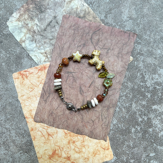 Meadow Pup Bracelet — close-up highlighting the puppy charm with leaf and floral accents in warm amber tones