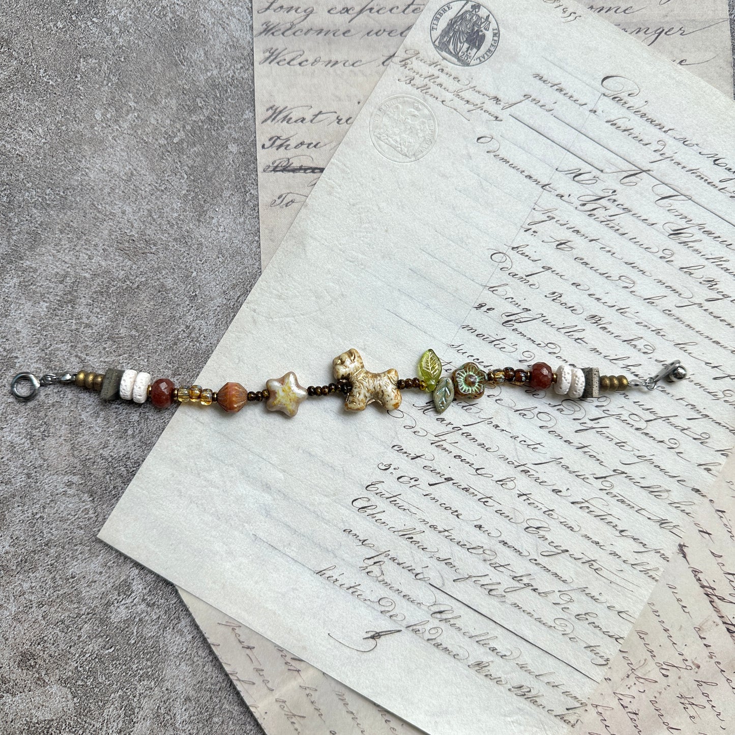 Meadow Pup Bracelet — circle layout on textured background with puppy, leaf, and floral accents