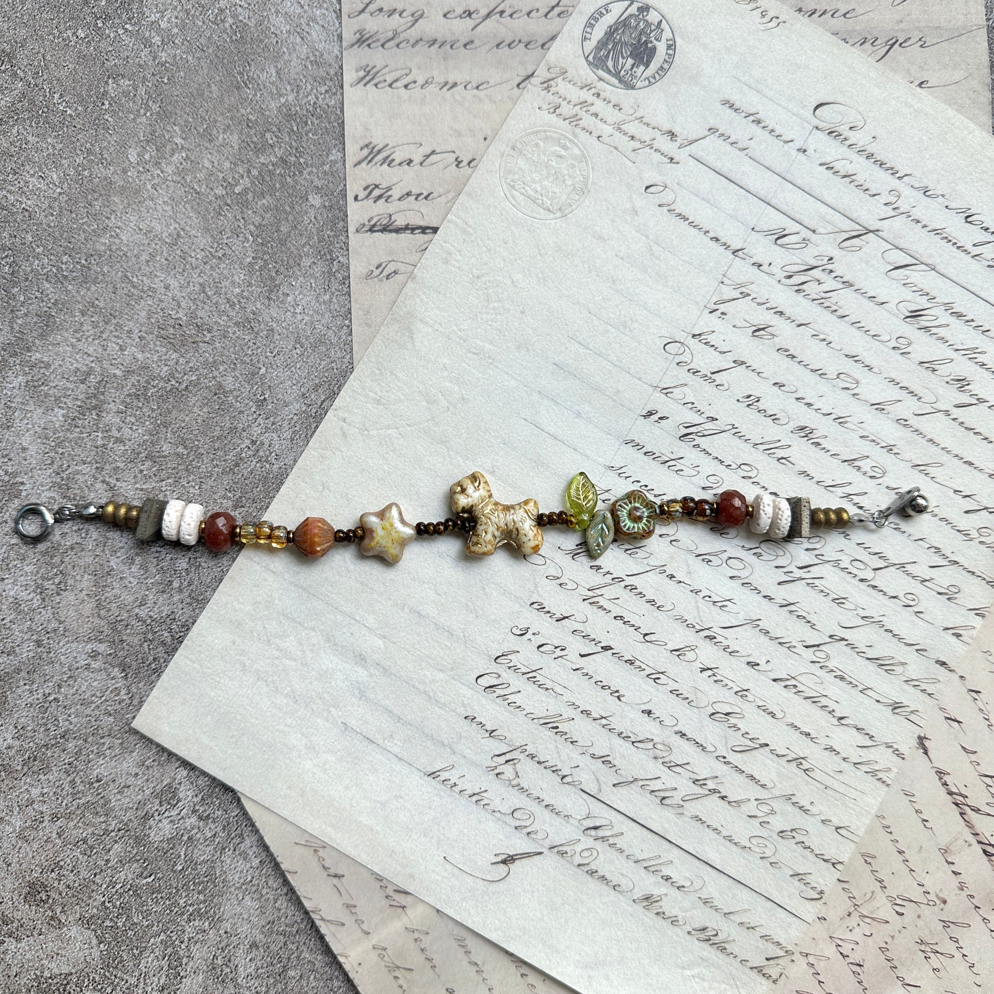 Meadow Pup Bracelet — circle layout on textured background with puppy, leaf, and floral accents