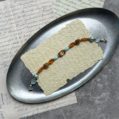 Aqua & Amber Drift Bracelet — flat lay on textured stone paper; sea-glass aqua and warm amber beads with gold accents and a nickel-free magnetic clasp 3