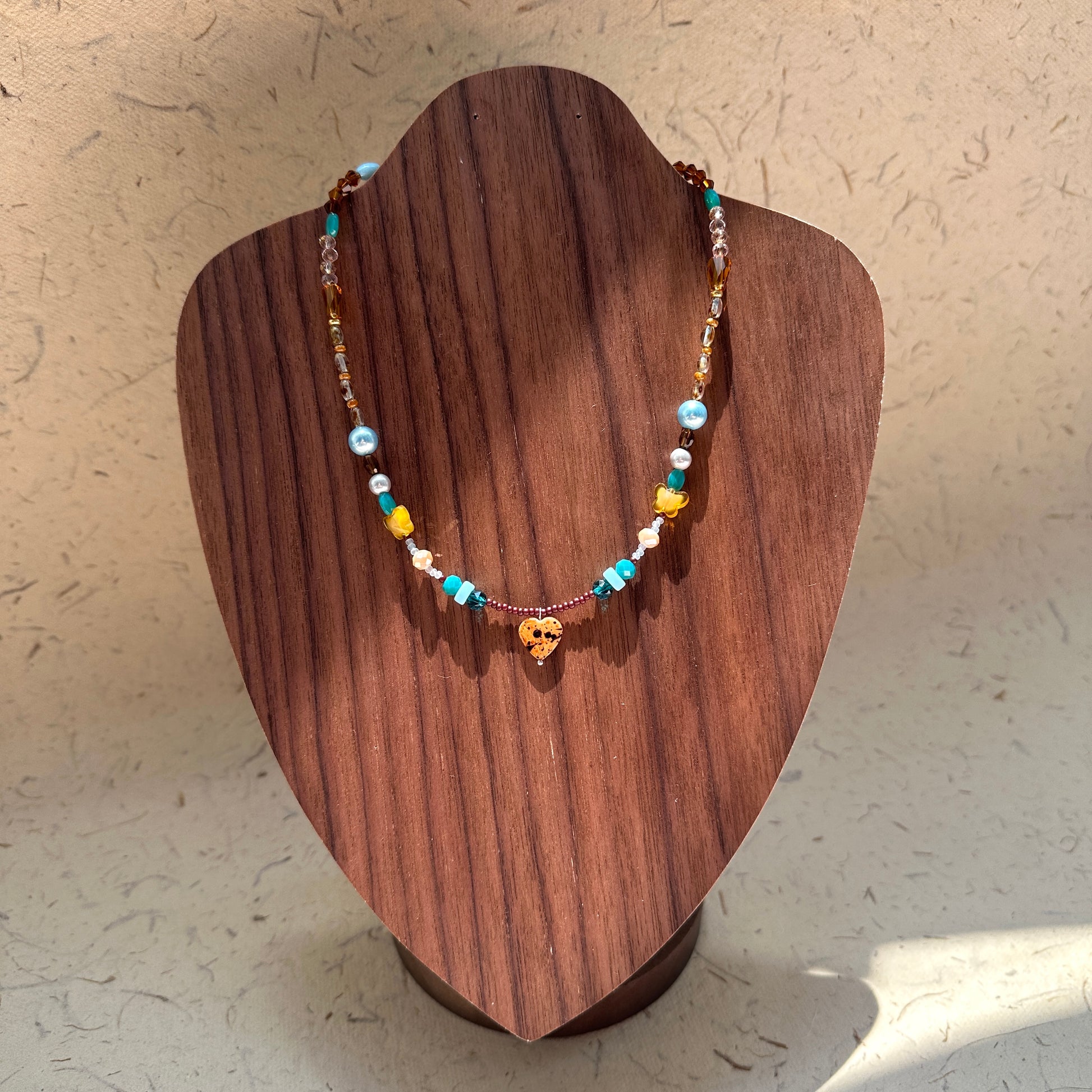 Model wearing Amber Heart Charm Necklace, romantic earth-and-sea palette