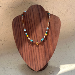 Model wearing Amber Heart Charm Necklace, romantic earth-and-sea palette
