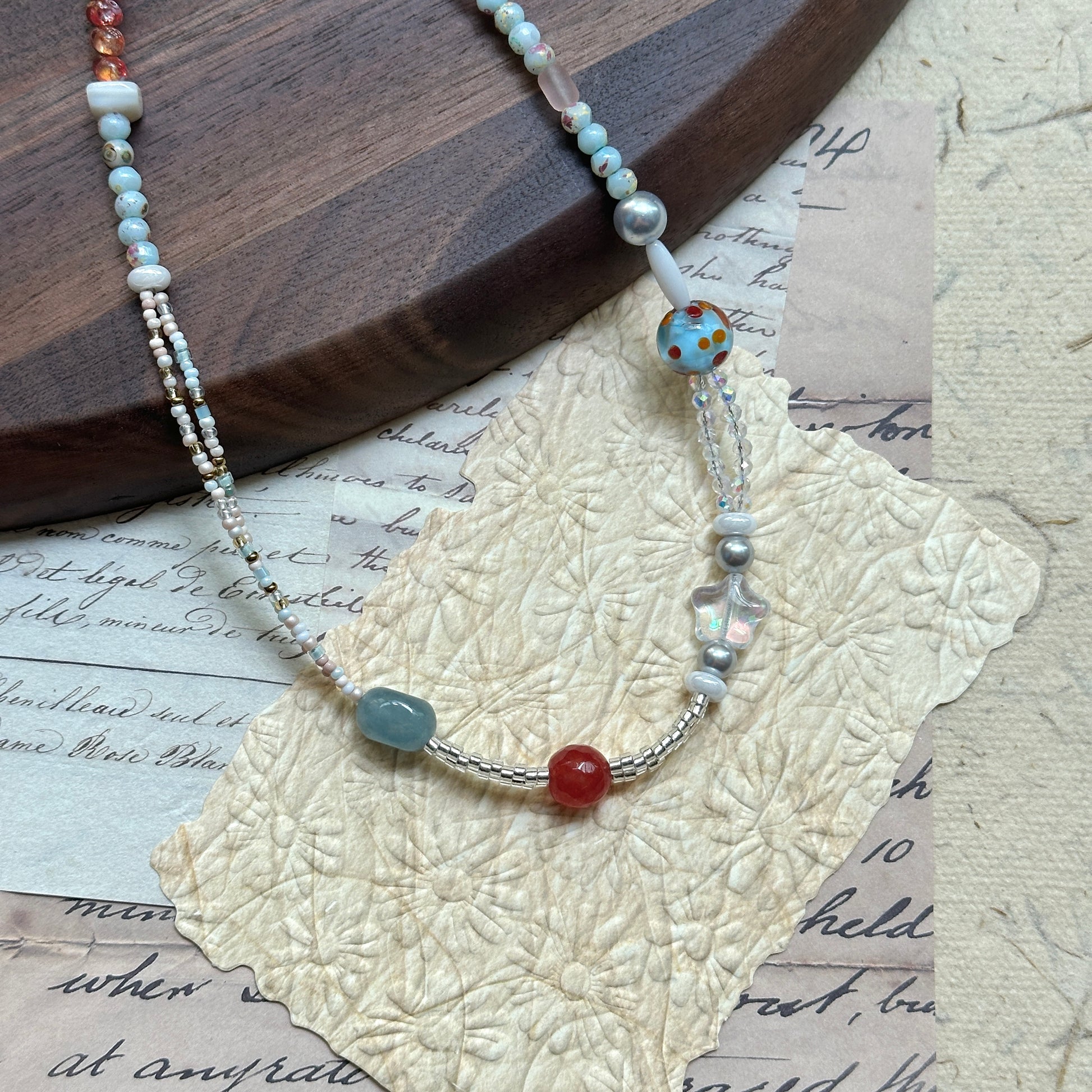 Candy Sky Necklace — angled close-up on textured paper showing the star charm and polka-dot lampwork bead detail