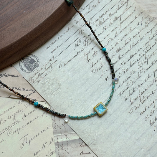Azure Blossom Necklace — close-up showing the floral ceramic charm and bead texture in turquoise and earthy brown tones