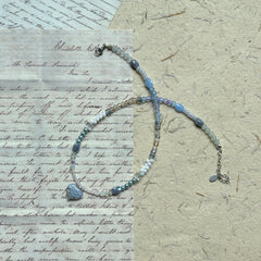 Moonlit Heart Necklace — angled view on textured paper showing bead arrangement and moonlit sparkle