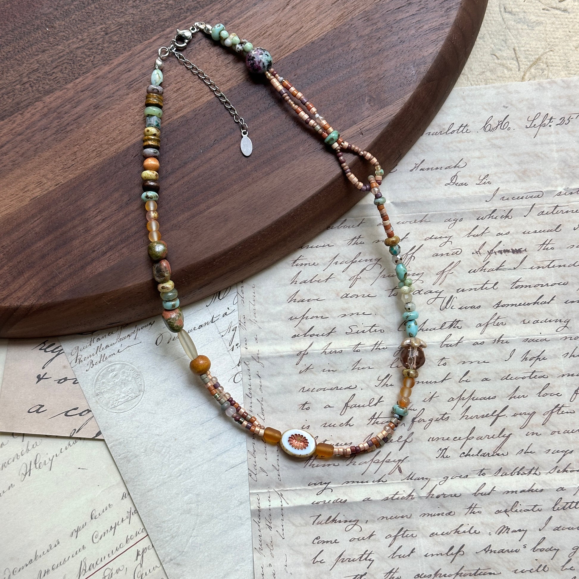 Sunlit Meadow Necklace — angled close-up beside a wooden tray showing the sunflower focal and mixed bead textures