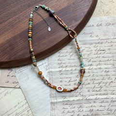 Sunlit Meadow Necklace — angled close-up beside a wooden tray showing the sunflower focal and mixed bead textures