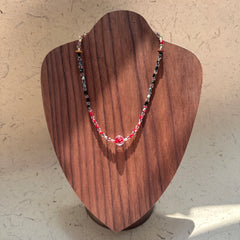 Crimson Eclipse Necklace on wood display bust — red and black glass beads with a crimson orb centerpiece