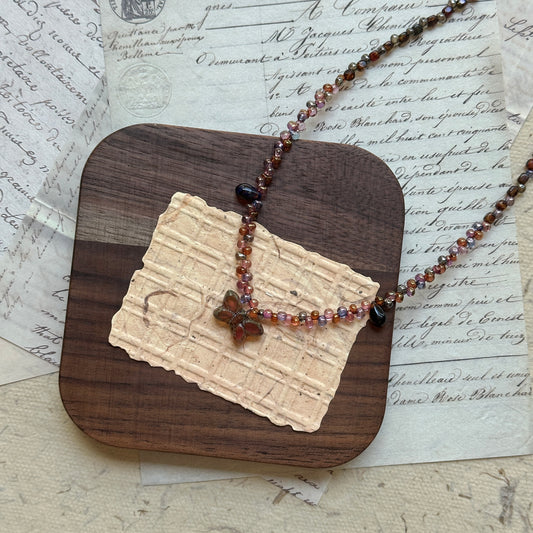 Handcrafted Twilight Bloom Necklace – beaded design in gradient wine-red and amber tones, featuring central flower charm.