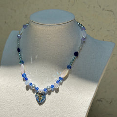 Midnight Starburst Necklace worn on display bust, highlighting elegant contrast of deep blue and pearl-white beads with golden starburst pendant