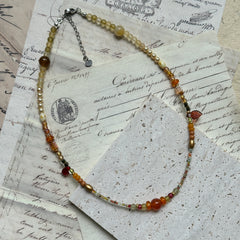 Golden Nectar Necklace flat lay with radiant amber cluster, gold bead mix, and delicate leaf accent